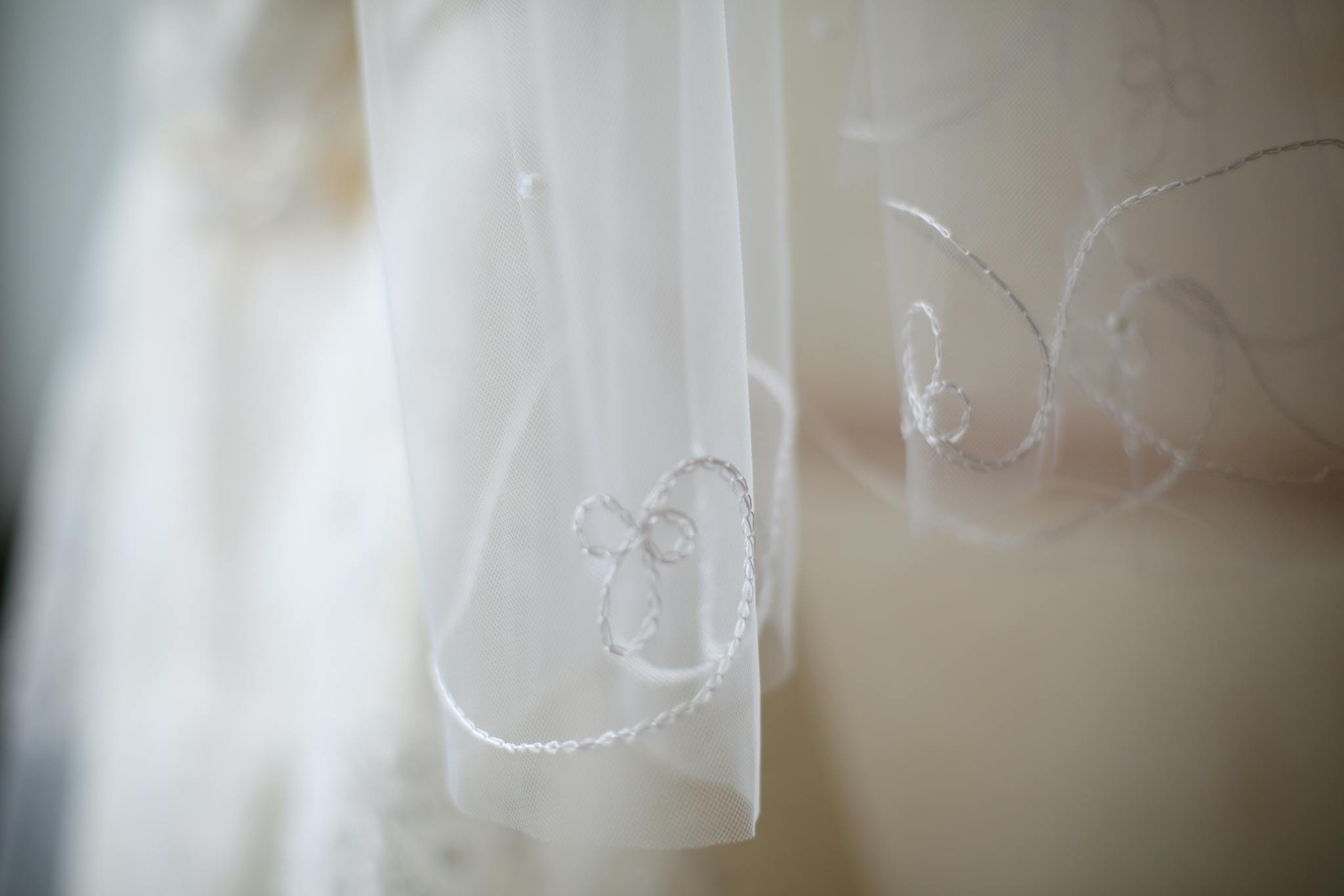 Elegant close-up of a white lace veil featuring intricate floral embroidery, perfect for weddings.